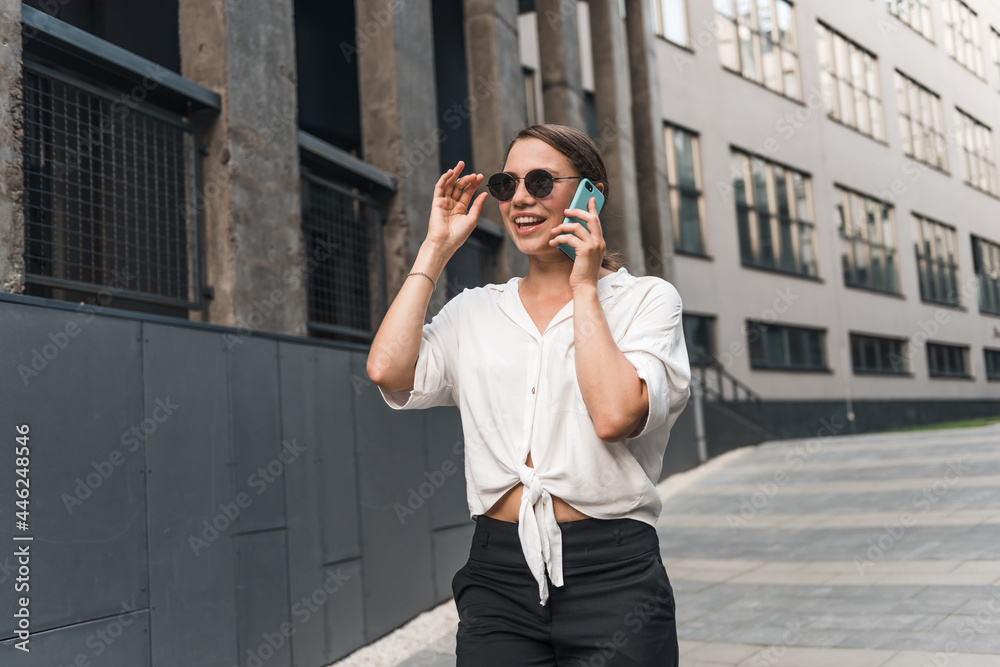 Business woman in the city talking on speaker with smartphone. Close up successful woman using phone at street. Business woman in the city talking on speaker with smartphone. Close up successful woman using phone at street.