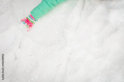 Arm Hand child wearing pink mitten glove on snow.