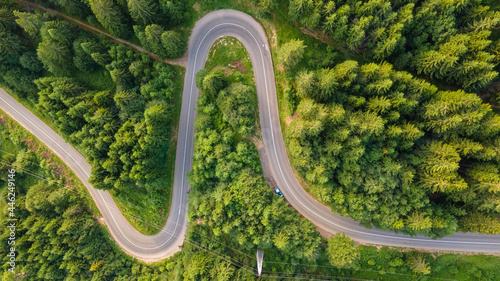 Aerial view of countryside road passing through the green forrest and mountain. Green pine and fir trees forest. Beautiful mountain road.