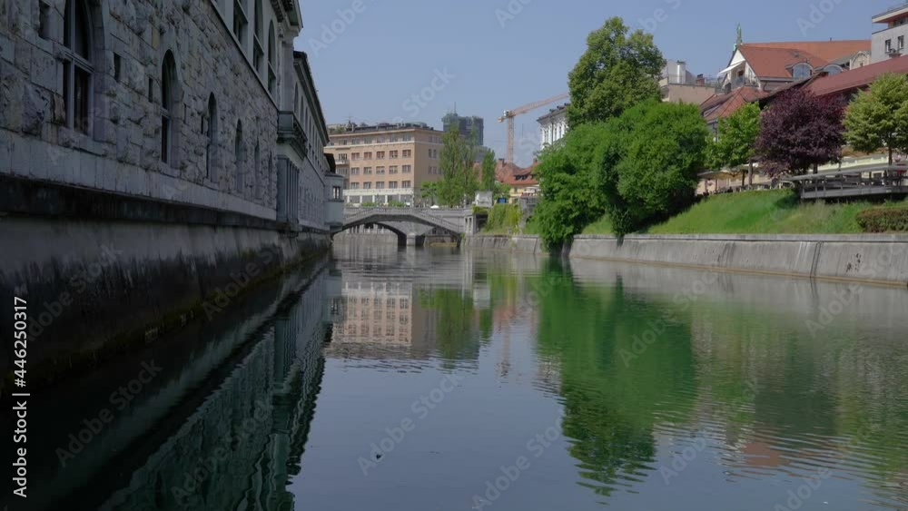 Low angle view of Ljubljanica river and famous Triple Bridge in Ljubljana city, Slovenia. Beautiful vintage architecture. Zoom in, real time Low angle view of Ljubljanica river and famous Triple Bridge in Ljubljana city, Slovenia. Beautiful vintage architecture. Zoom in, real time