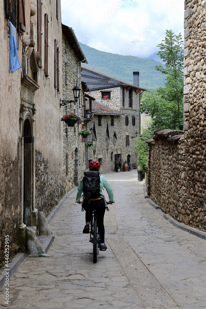 Detail of healthy woman riding her bike through the stone houses and woods of Anciles, a village nearby Benasque, one of the most amazing spots of the Spanish Pyrenees mountains.