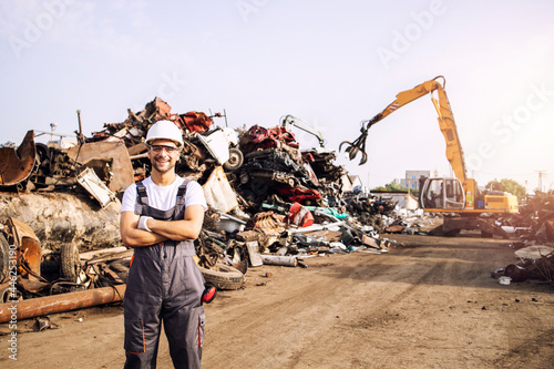 Portrait of junkyard worker standing in scrap metal recycling center.