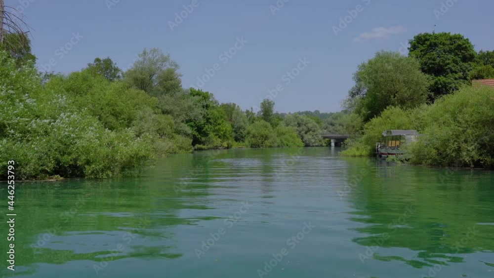 Navigating on Ljubljanica river near Ljubljana city, Slovenia. Unique perspective of green suburb on hot summer day. Trees covering river bank. Real time, forward moving, wide angle Navigating on Ljubljanica river near Ljubljana city, Slovenia. Unique perspective of green suburb on hot summer day. Trees covering river bank. Real time, forward moving, wide angle