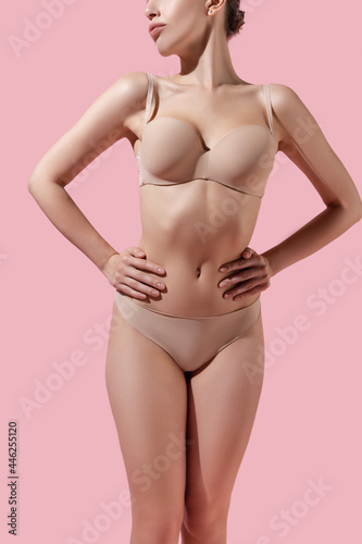 Young woman in lingerie isolated over pink studio background. Beauty, fitness, diet, sports, plastic surgery and aesthetic cosmetology concept.