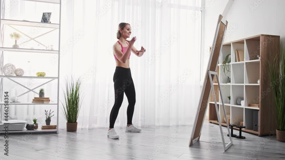 Fitness. Dancer exercising. Active hobby. Home training. Fit young woman in sport clothes practicing moves at mirror in light studio interior. Fitness. Dancer exercising. Active hobby. Home training. Fit young woman in sport clothes practicing moves at mirror in light studio interior.