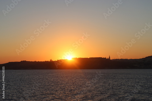 Maltese sunset from mediterranean sea, view on Gozo island from parome boat, way back home