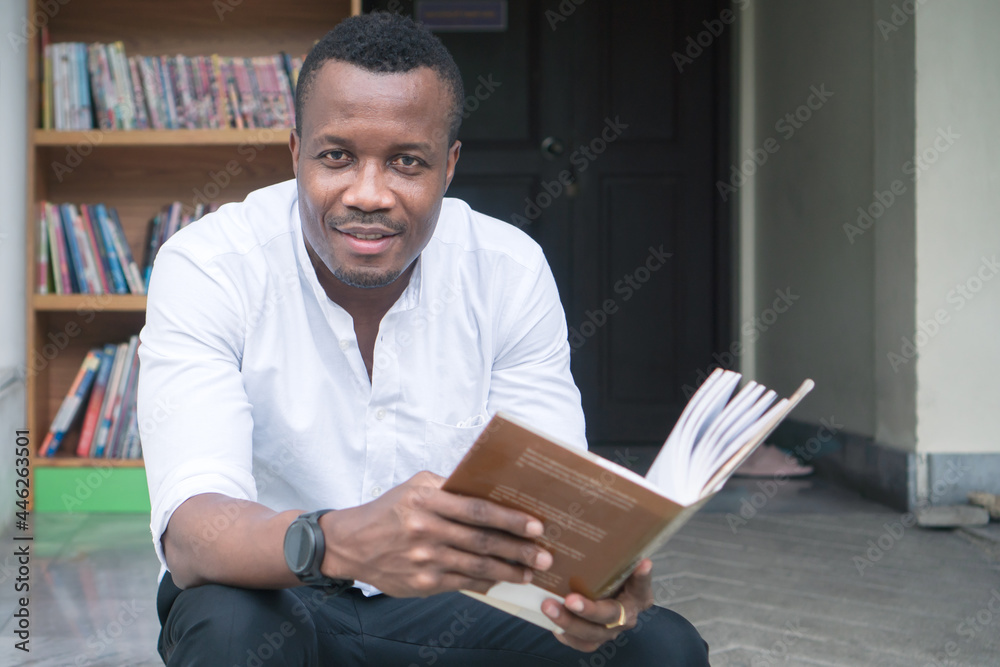 young man sitting reading a book at the library. young man sitting reading a book at the library.