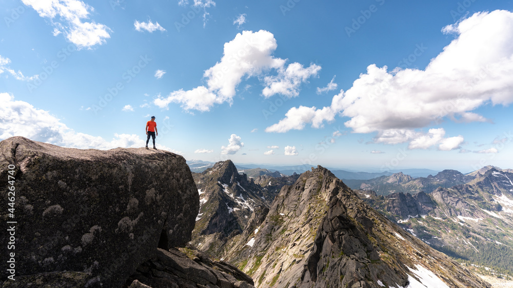 a man on the top against the background of mountains. A tourist on a sunny day hike.