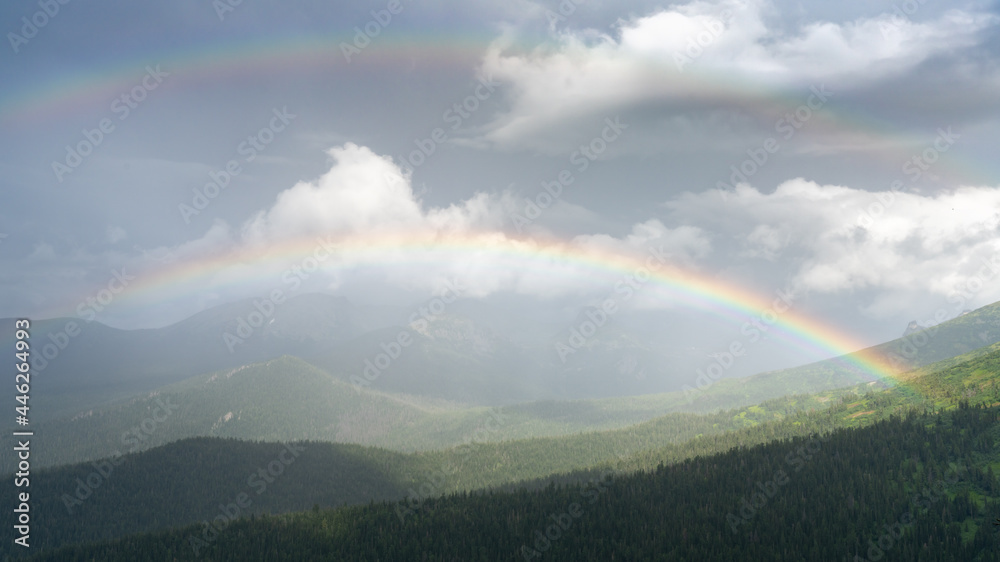 double rainbow in the mountains. Green forest in summer in cloudy weather