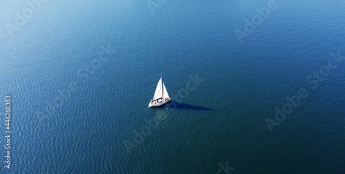 Aerial view of a white yacht with a sail. Ship in the blue sea