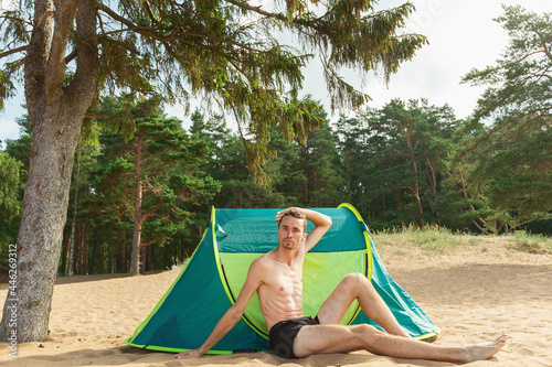 Young man sitting by tent ant posing © Alexandr