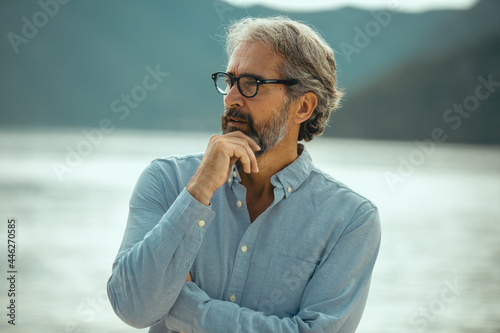 Portrait of pensive senior man at beach looking away.