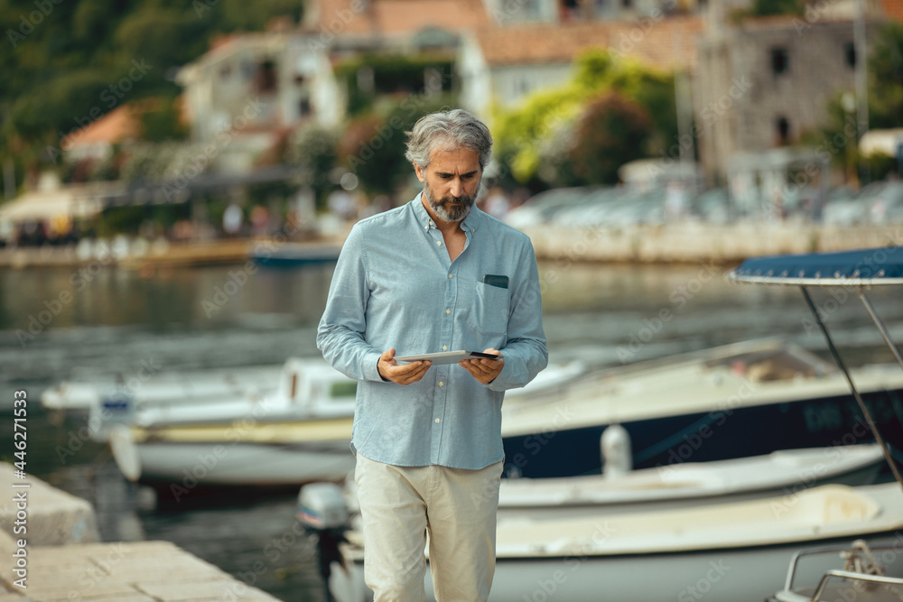Portrait of retirement handsome senior man holding tablet computer on seafront