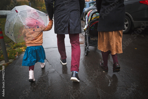 An unrecognizable family walks in a rainy autumn city.
