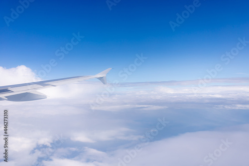blue sky with clouds and the wing of a flying plane