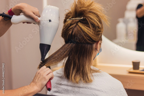 woman with face mask getting blow dry in hair salon