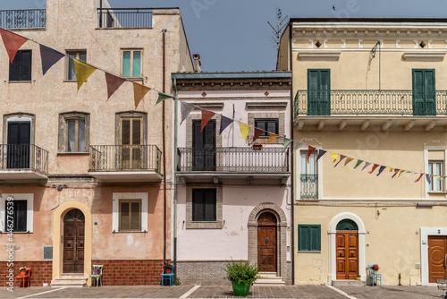 June 2021, San Vito Chietino, Italy. Main square of San Vito Chietino, old colored chairs next to the entrance doors of the houses, for tired travelers and to support flower pots.