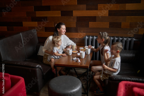 Mother with children drinking hot chocolate and latte at a local coffee shop. They are smiling and having fun. Motherhood concept