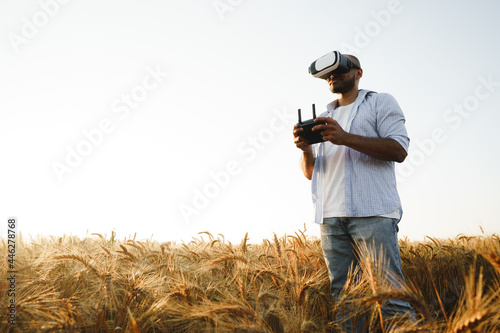 Photo Young man standing in a wheat field at sunset in virtual reality glasses