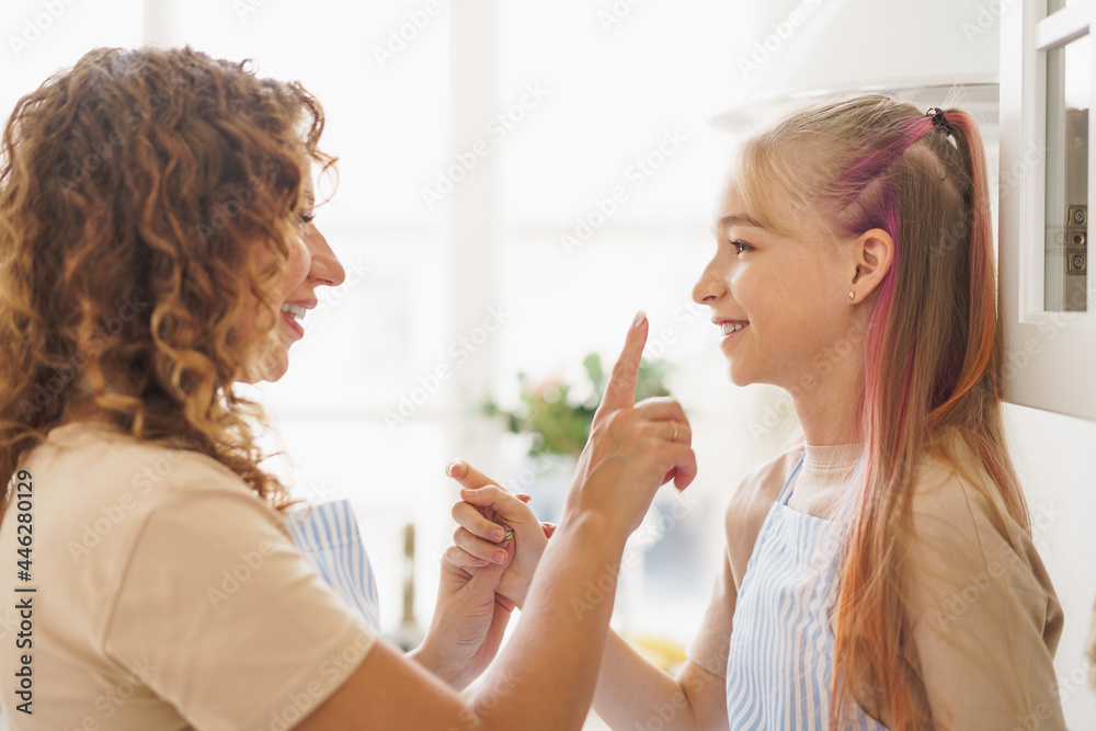 Portrait of a teen girl with her mother at home in kitchen