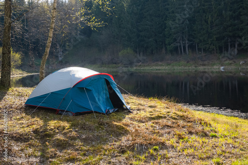 Camping tent set up near the lake in the forest. Relaxing in a camp site outdoors.