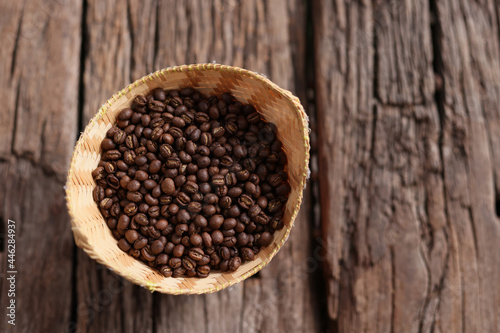 Coffee Beans Peaberry small size picking in bamboo basket. log wooden background. Selective focus on foreground with copy space.
