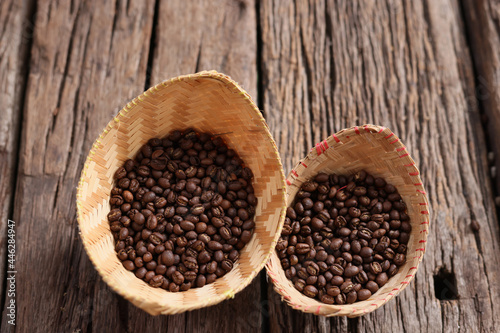 hand hold Coffee Beans Peaberry small size picking . a cup and log wooden background. Selective focus on foreground with copy space.