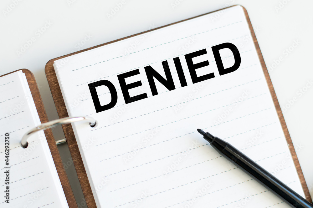 a notebook with the text DENIED on a white background next to a black marker a notebook with the text DENIED on a white background next to a black marker