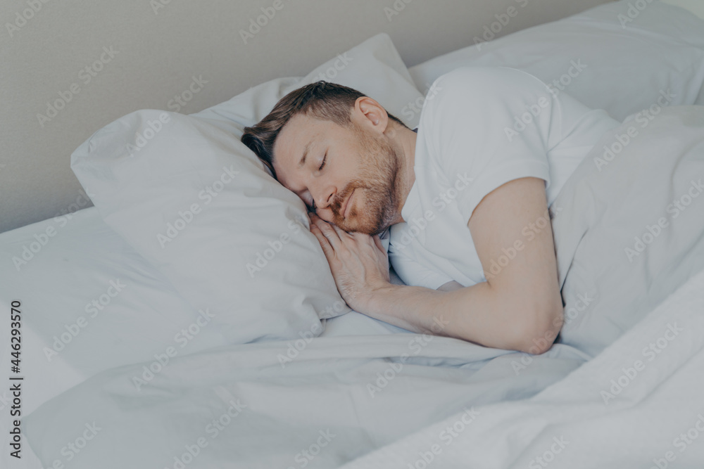 Handsome young man comfortably sleeping in bed at home Handsome young man comfortably sleeping in bed at home