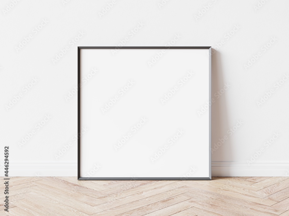 Empty square picture frame with thin dark border laying on wooden parquet floor, white wall in background. 3D illustration. Empty square picture frame with thin dark border laying on wooden parquet floor, white wall in background. 3D illustration.