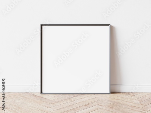 Fototapeta Naklejka Na Ścianę i Meble -  Empty square picture frame with thin dark border laying on wooden parquet floor, white wall in background. 3D illustration.