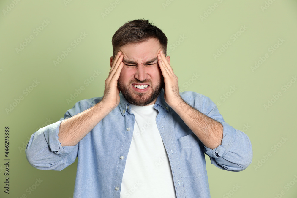 Man suffering from migraine on light green background Man suffering from migraine on light green background