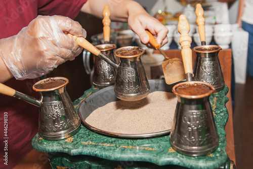 Woman makes turkish coffee on a coffee machine with sand in cezve. Oriental, east coffee photo