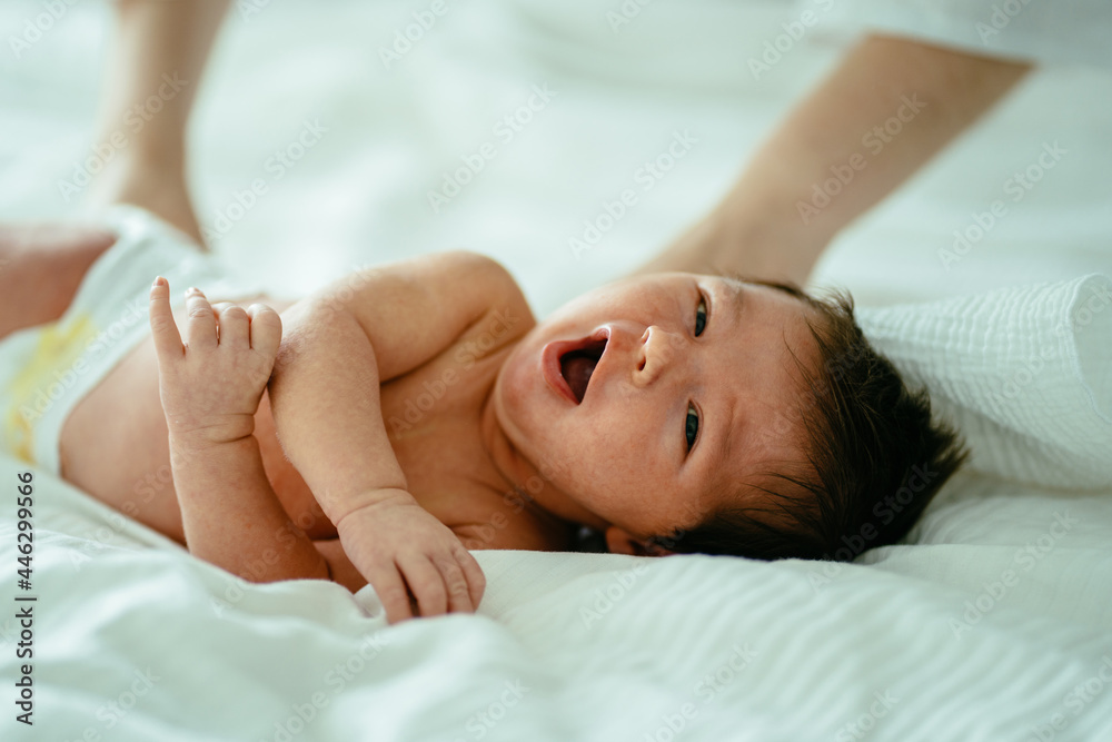 Newborn baby girl. Mothers hands calm down her mixed race newborn daughter on bed with white blanket. Family, love, calming, happy and new life concept. Newborn baby girl. Mothers hands calm down her mixed race newborn daughter on bed with white blanket. Family, love, calming, happy and new life concept.