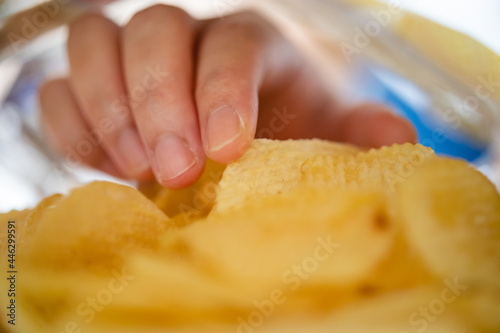 Hand picking potato chips inside snack bag