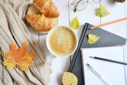 Cup of coffee with autumns leaves, diary and book on the white wooden texture. Back to school. September, October. Write and read, study  in relaxing atmosphere.    