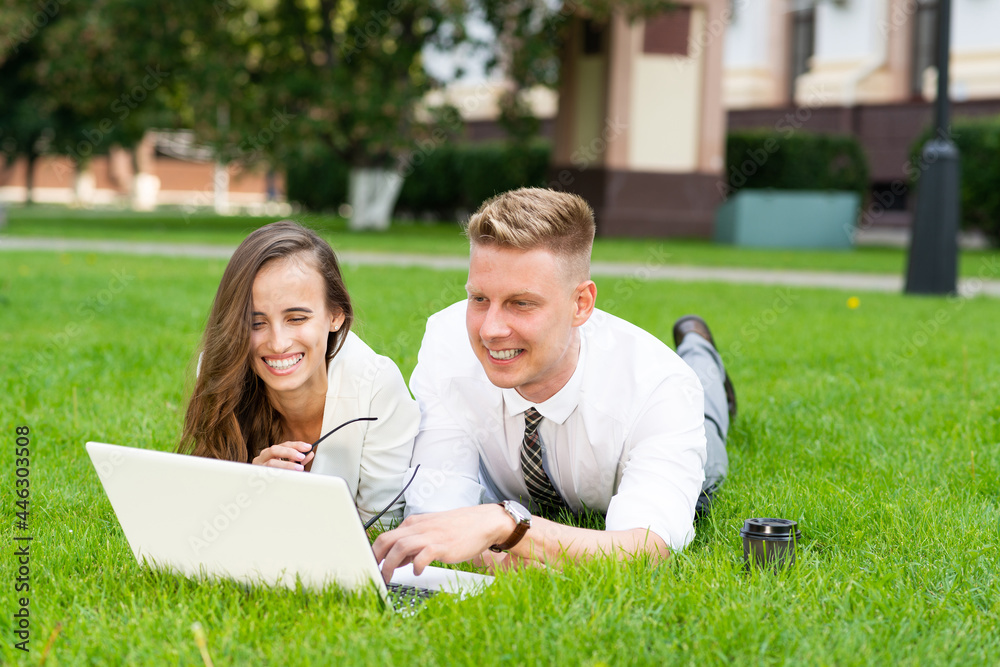 businessman and businesswoman with a laptop in a city park businessman and businesswoman with a laptop in a city park