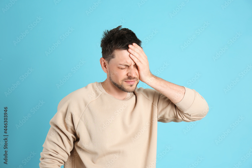 Man suffering from terrible migraine on light blue background Man suffering from terrible migraine on light blue background