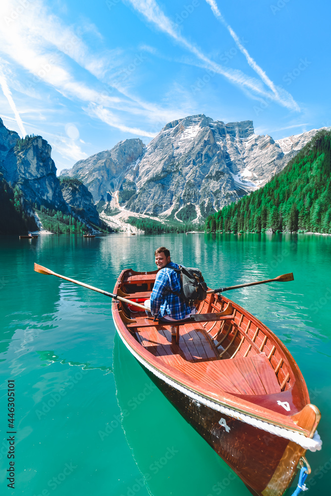 man rowing in big wooden boat at mountain lake