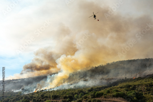 Helicóptero de bomberos en acción apagando un incendio en la montaña, en Leon. España.