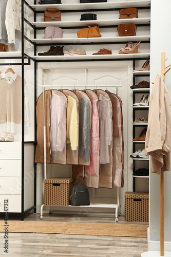 Garment bags with clothes on rack in dressing room