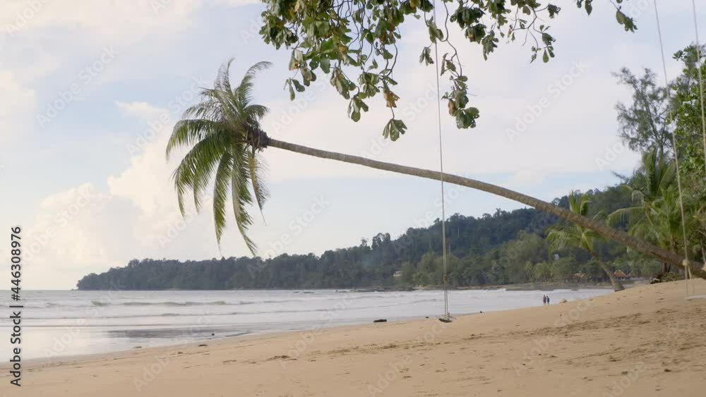 Empty swing on a tropical beach. Swings on a palm tree at paradise sand beach. People travel vacations fun concept. Girl in beautiful blue dress walks along beach. Strong independent woman in Asia. Empty swing on a tropical beach. Swings on a palm tree at paradise sand beach. People travel vacations fun concept. Girl in beautiful blue dress walks along beach. Strong independent woman in Asia.
