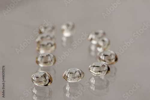 Transparent yellow capsules Vitamin D3, Omega, on glass background, table