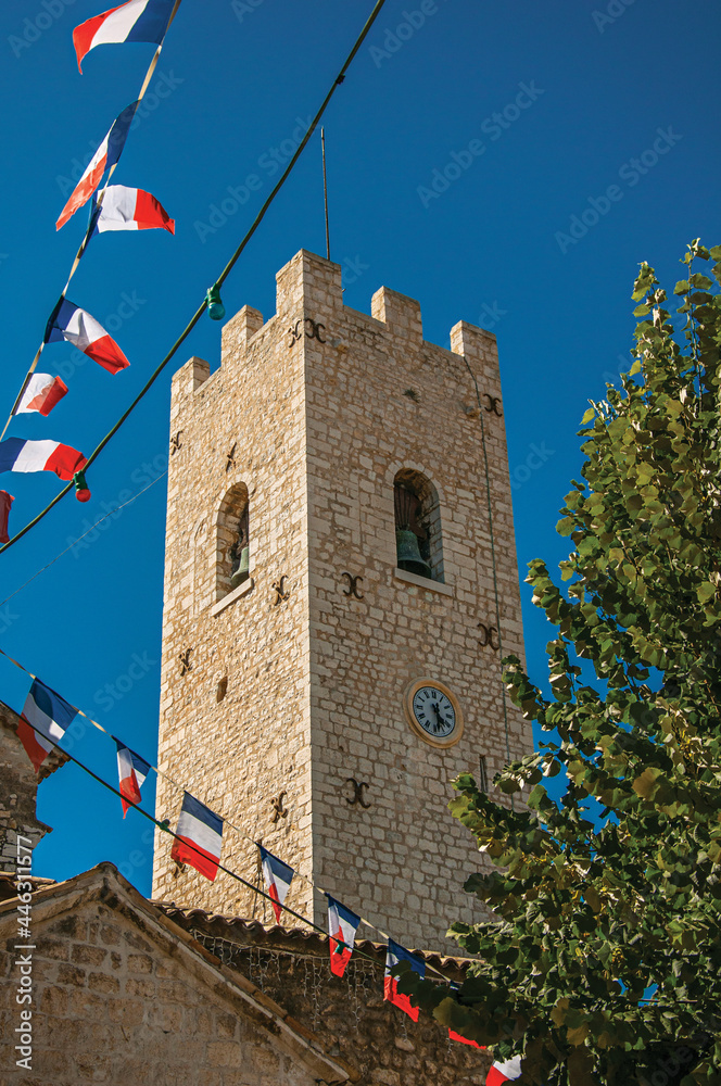 View of stone steeple tower next to church and flags in Vence, a stunning medieval hamlet completely preserved. Provence region, southeastern France.