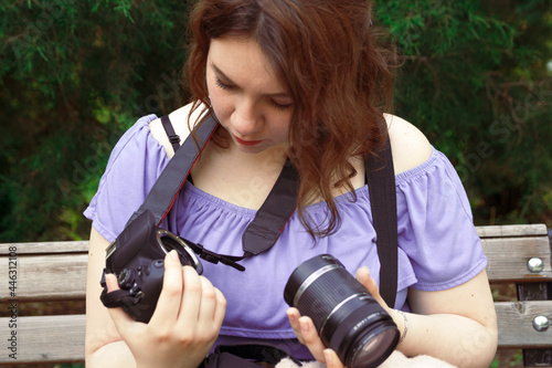 Young girl looking at DSLR and the lens. Camera issues concept