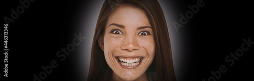 Fotografia Scary face expression of crazy Asian girl with evil smile on black background banner