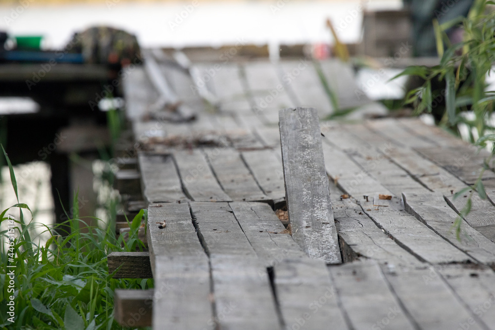 Wooden platform with a broken board going into the river Wooden platform with a broken board going into the river