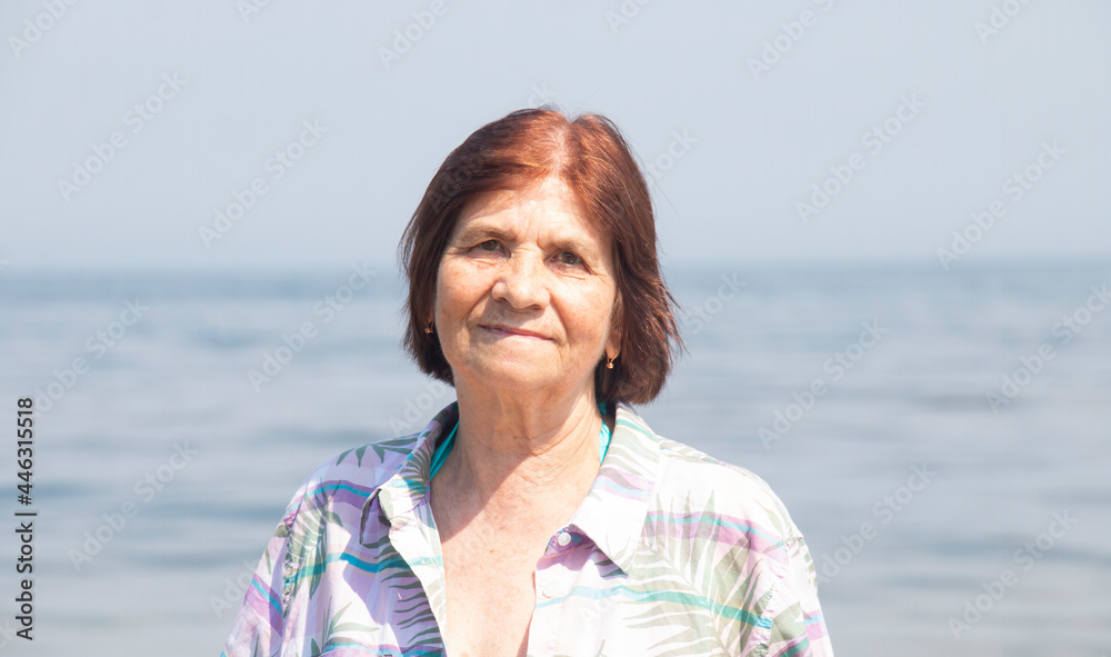 portrait of charming happy 72 year old woman by the sea in summer on a sunny hot day portrait of charming happy 72 year old woman by the sea in summer on a sunny hot day