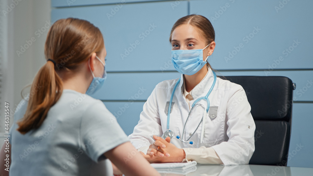 Lady medical consultant in facial mask and white coat examines blonde patient talking Lady medical consultant in facial mask and white coat examines blonde patient talking