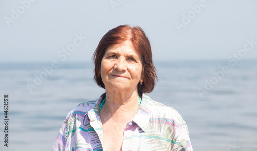 portrait of charming happy 72 year old woman by the sea in summer on a sunny hot day